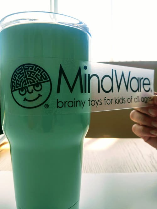 A custom clear vinyl decal featuring the MindWare Logo appied to a tumbler. 